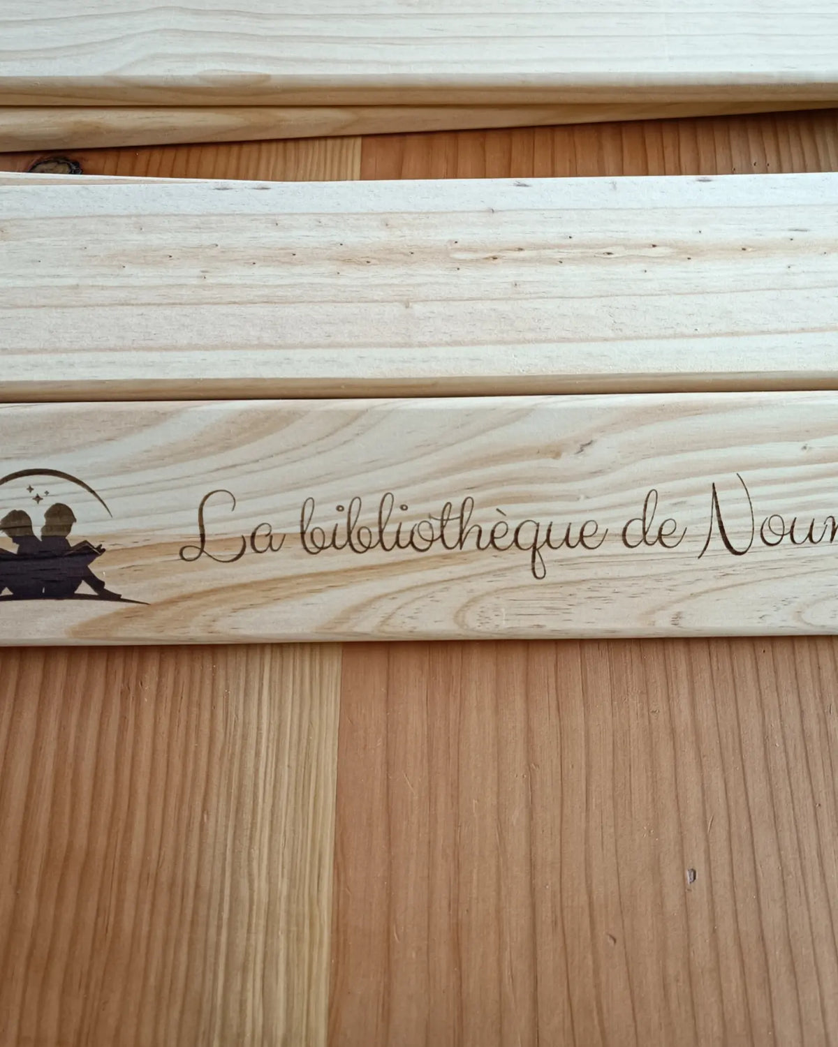 Gravure personnalisée au laser sur bibliothèque Montessori artisanale en bois massif.